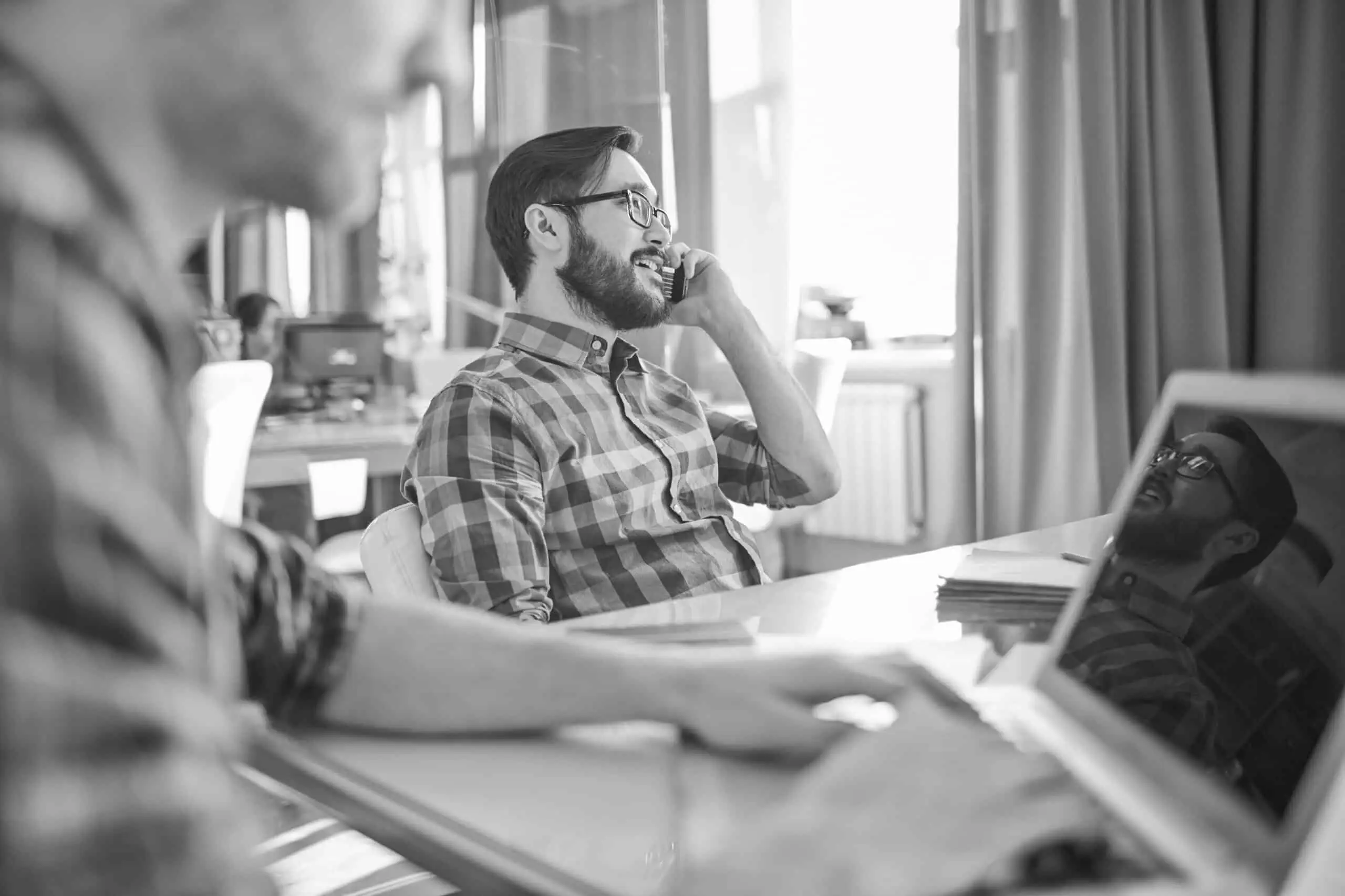 Young businessman sitting by workplace and speaking on the phone