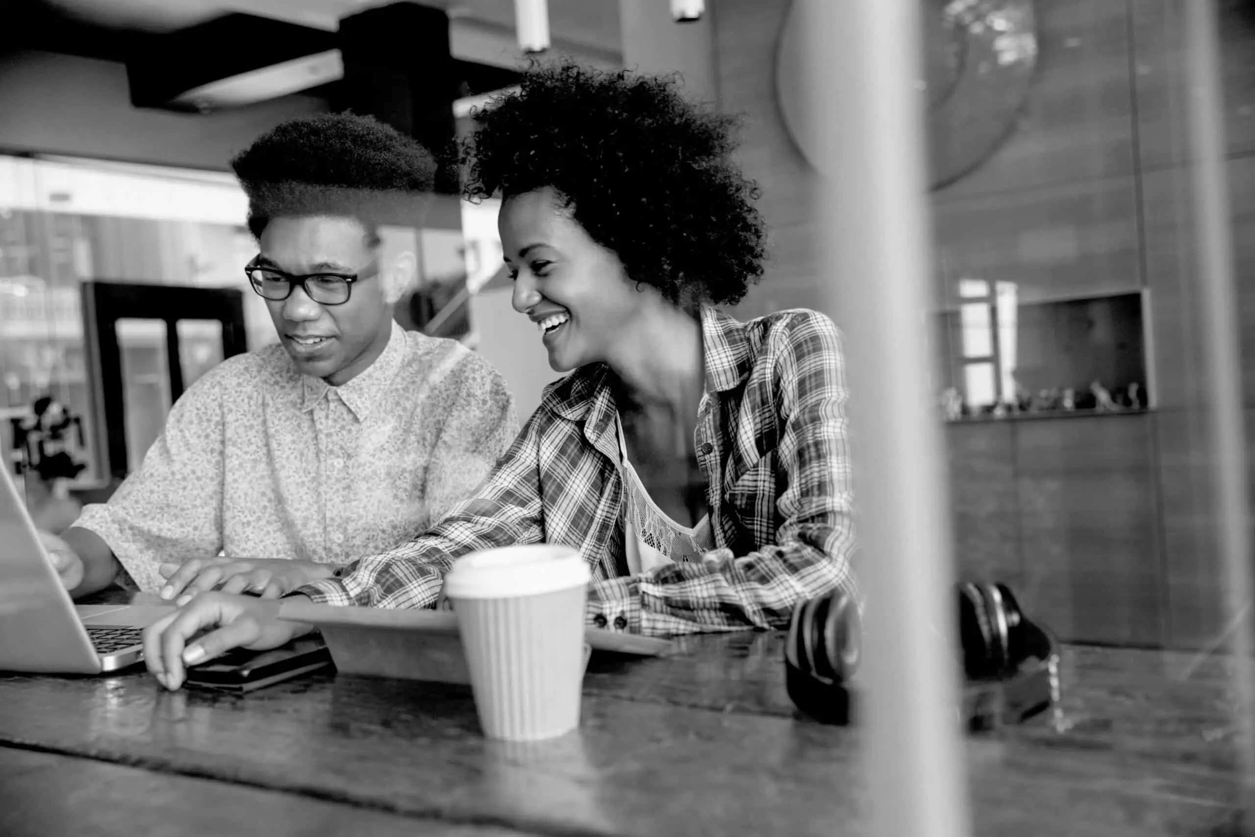 Two Young Businesspeople Working On Laptop In Coffee Shop