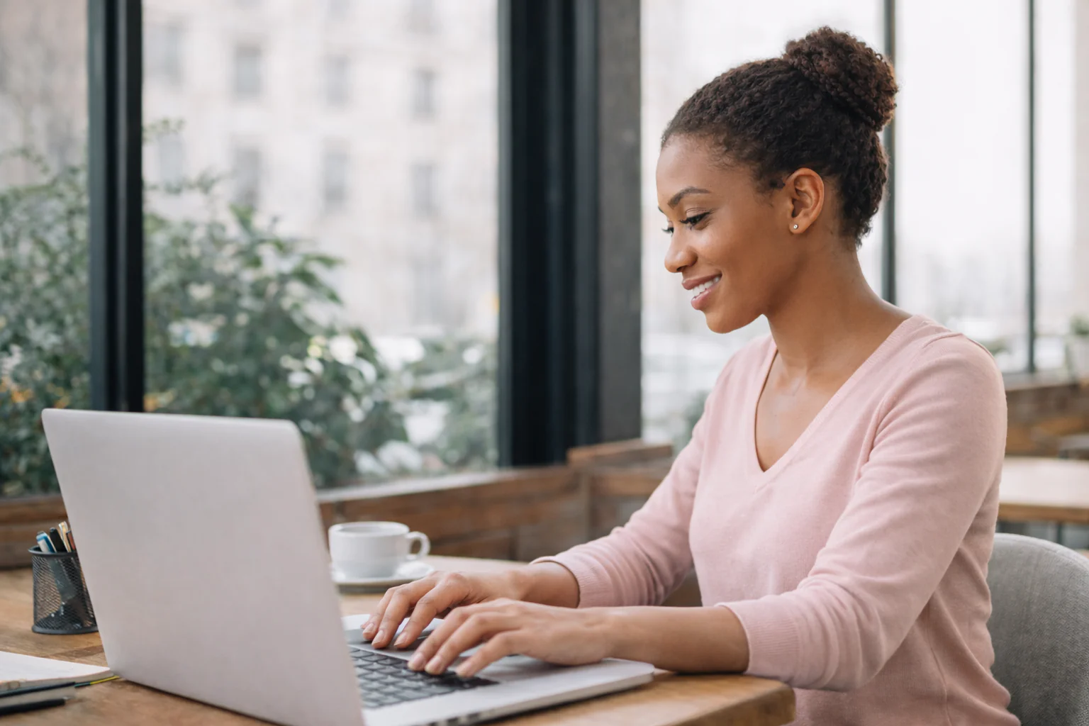 Woman working on a laptop in an office setting.